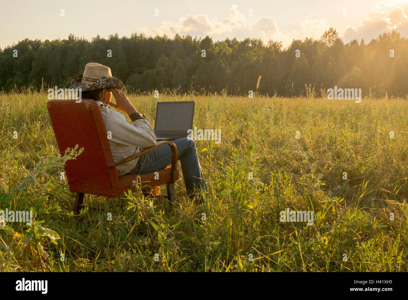 Mari man sitting on chair in field using laptop Stock Photo