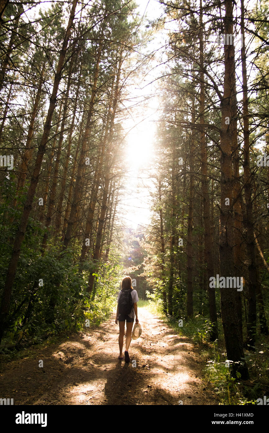 Caucasian woman walking on tree-lined forest path Stock Photo