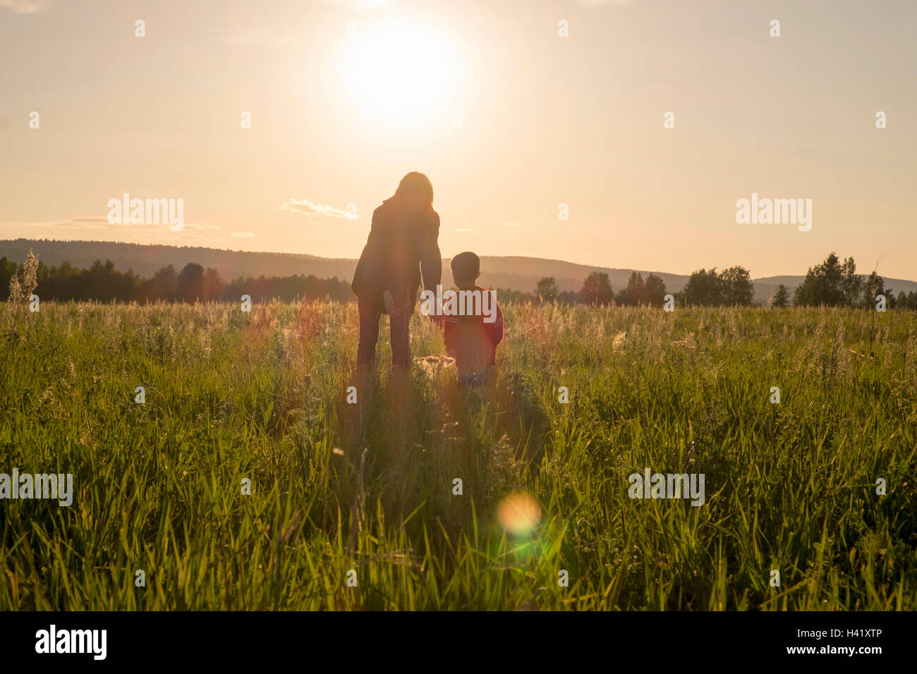 Woman and son standing in field at sunset Stock Photo