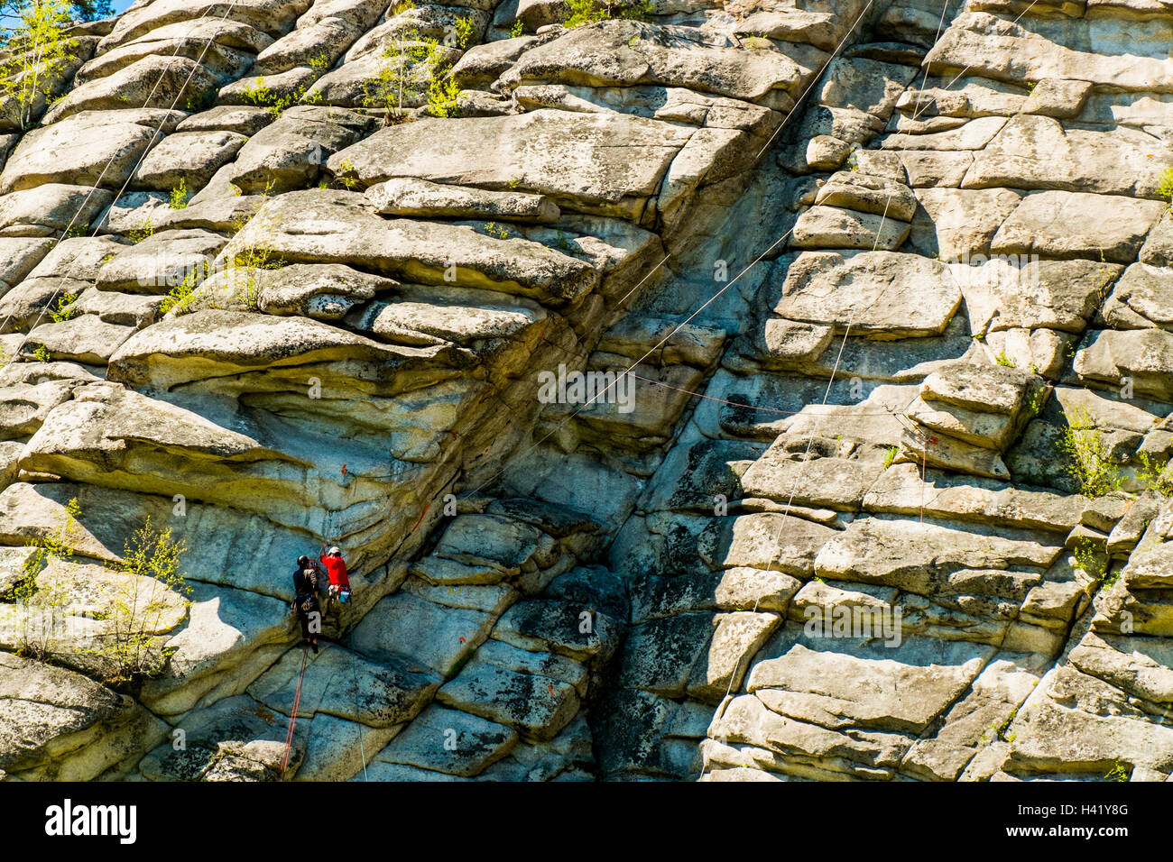 Caucasian friends climbing mountain with rope Stock Photo Alamy