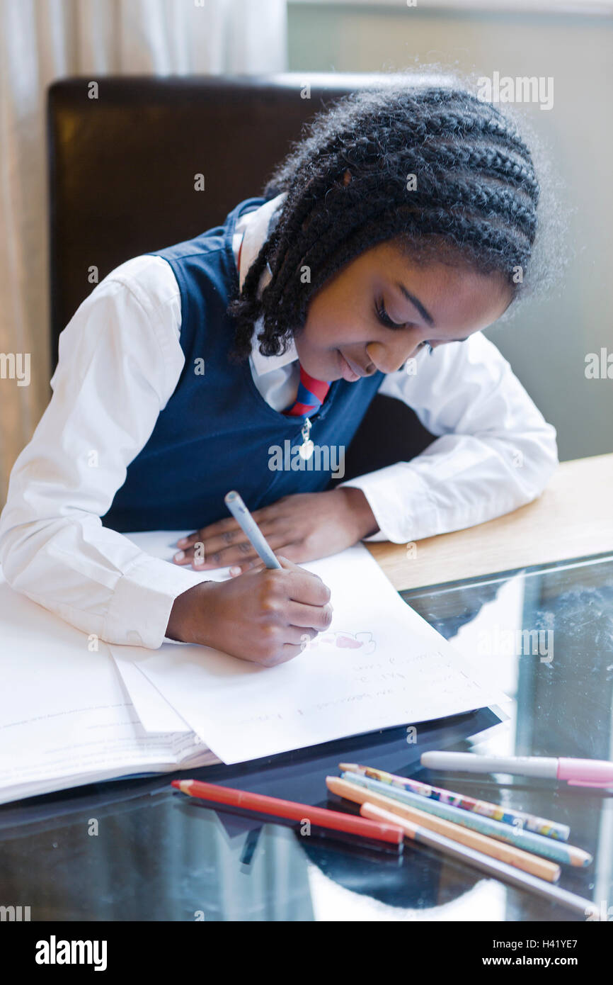 Black girl wearing school uniform doing homework Stock Photo