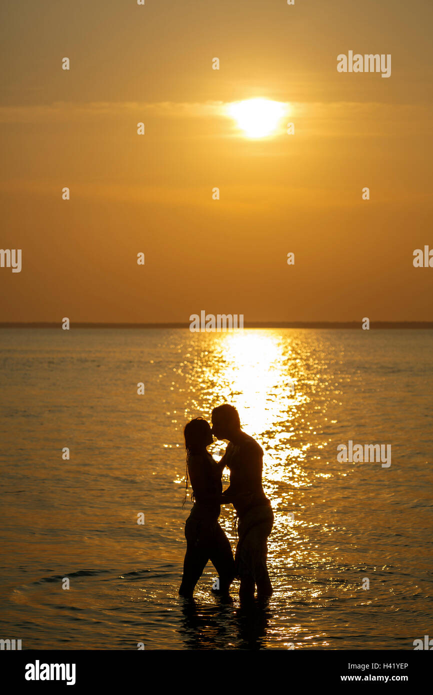 Silhouette of Caucasian couple kissing in ocean at sunset Stock Photo ...