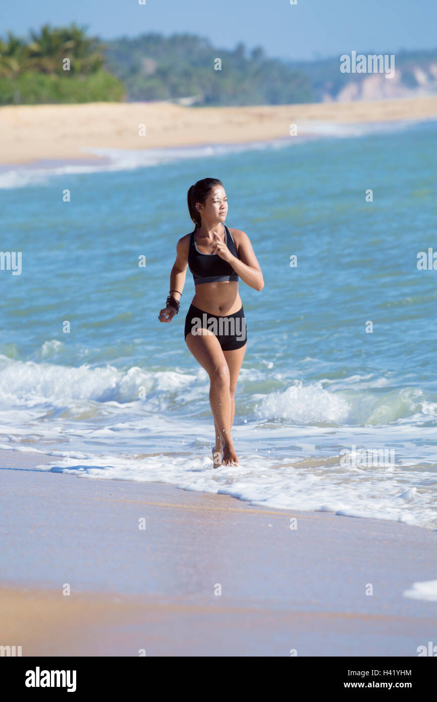 Mixed Race girl running on beach Stock Photo