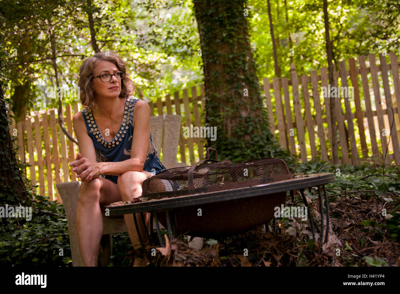 Caucasian woman sitting in backyard near fire pit Stock Photo