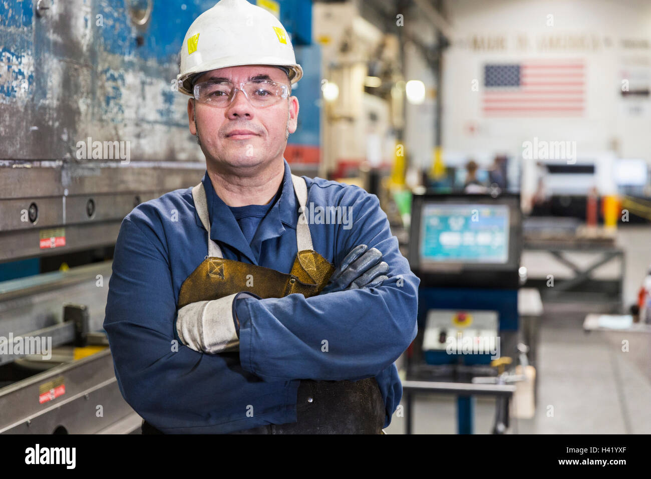 Serious Hispanic worker posing in factory Stock Photo