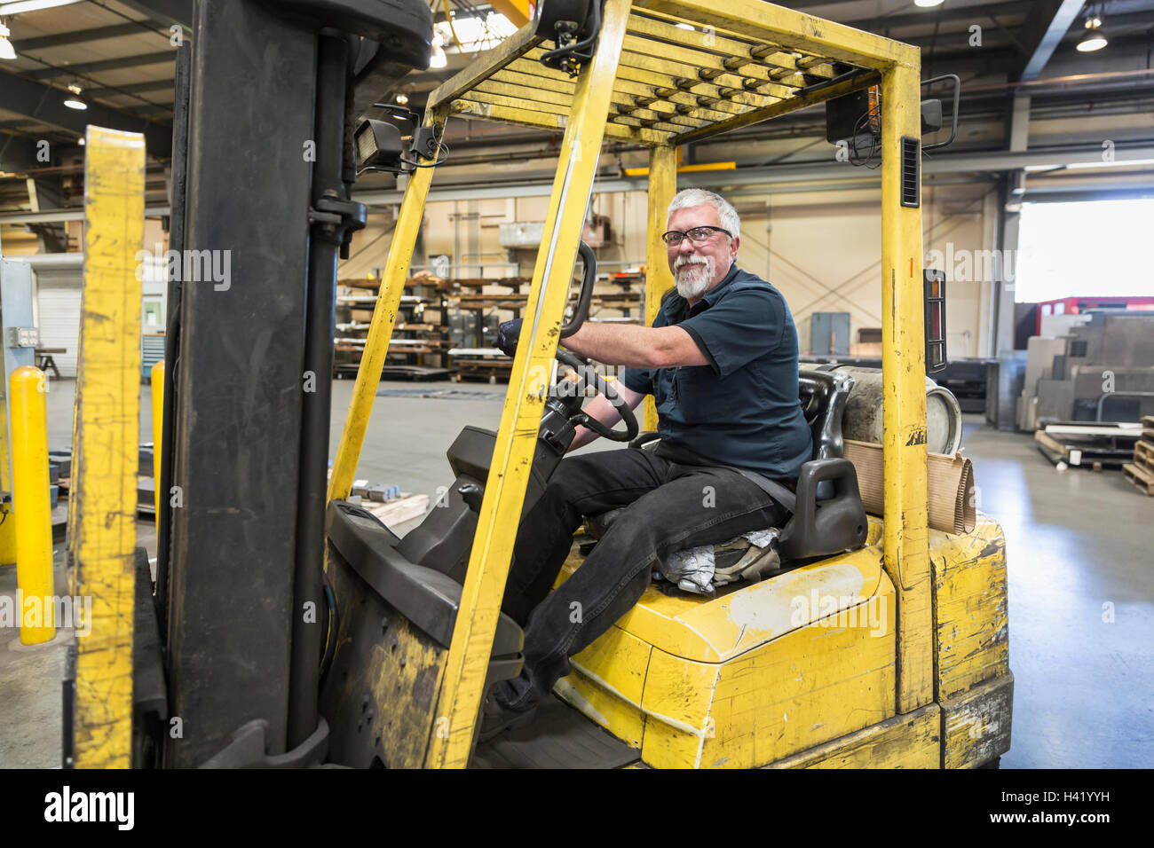 Caucasian worker driving forklift in factory Stock Photo