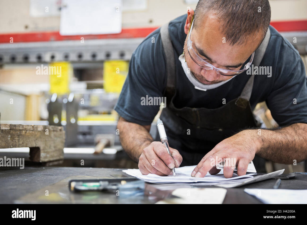 Hispanic worker writing on paperwork in factory Stock Photo