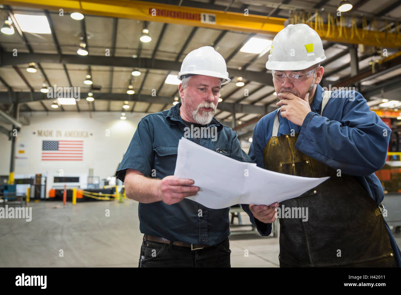 Workers examining paperwork in factory Stock Photo