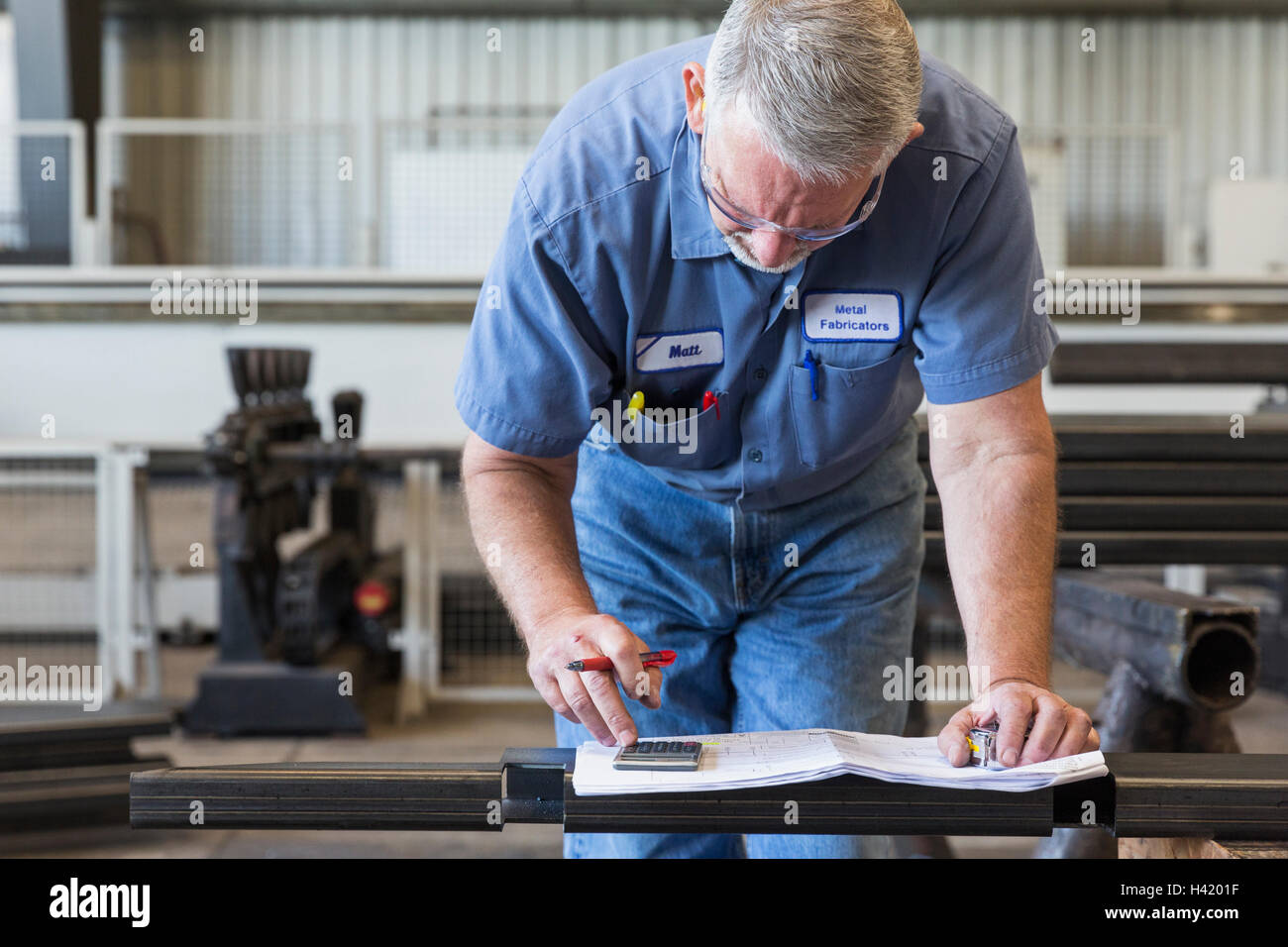 Caucasian worker using calculator in factory Stock Photo