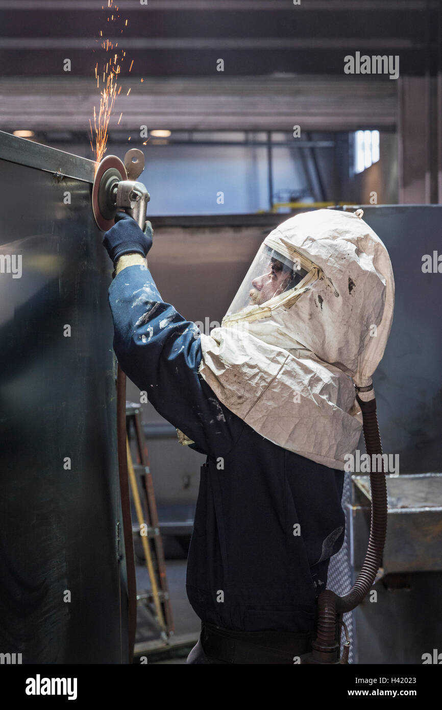 Caucasian worker grinding metal container in factory Stock Photo