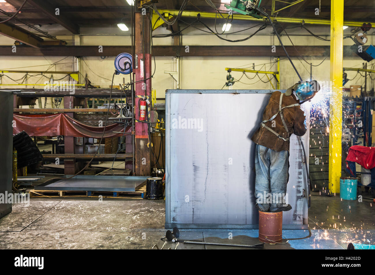 Asian worker grinding metal container in factory Stock Photo