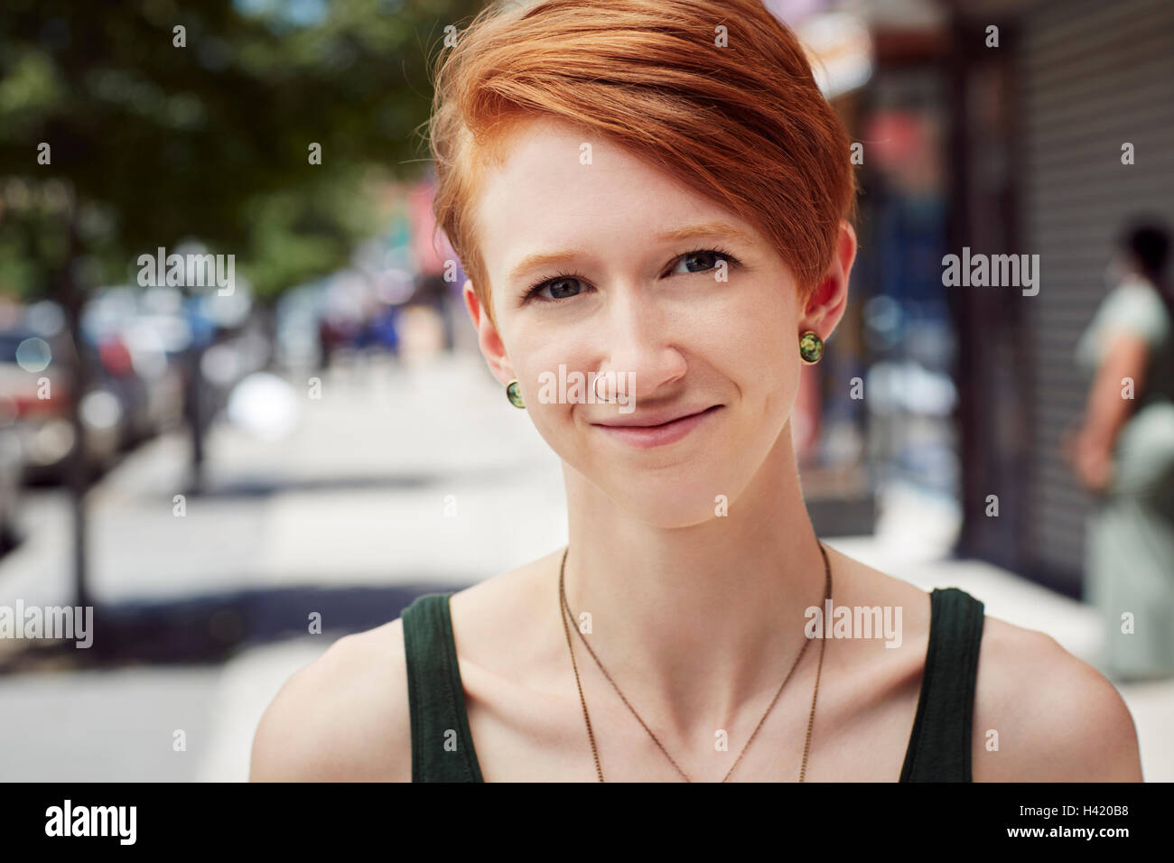 Caucasian woman with nose ring smiling on city sidewalk Stock Photo