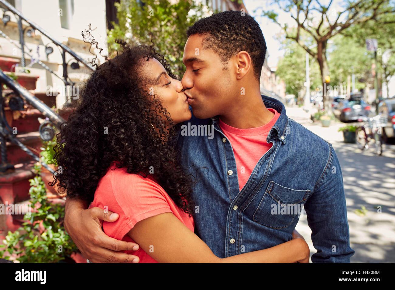 Smiling couple kissing on city sidewalk Stock Photo