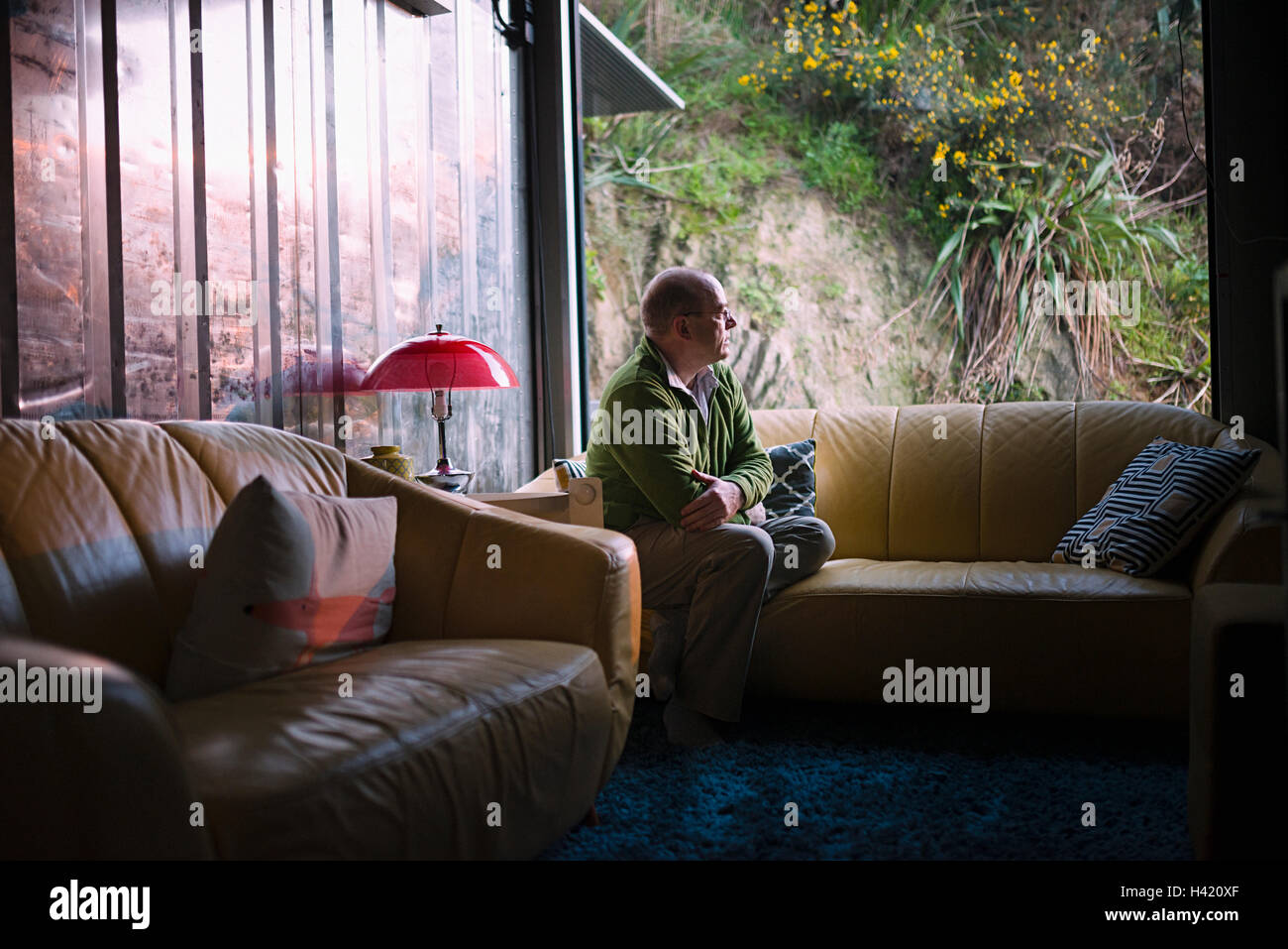 Pensive Caucasian man sitting on sofa near window Stock Photo