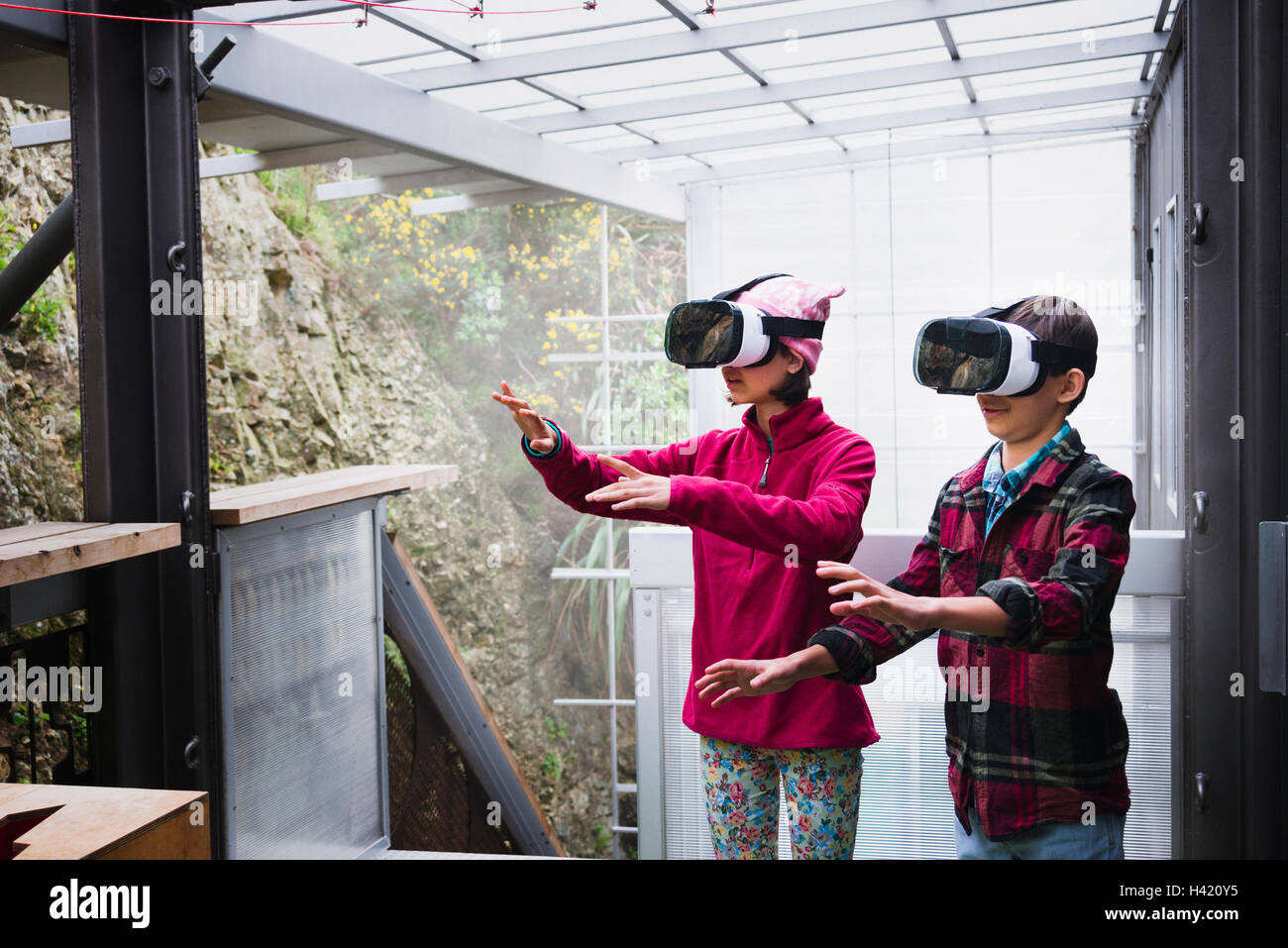 Mixed Race brother and sister using virtual reality goggles on veranda Stock Photo