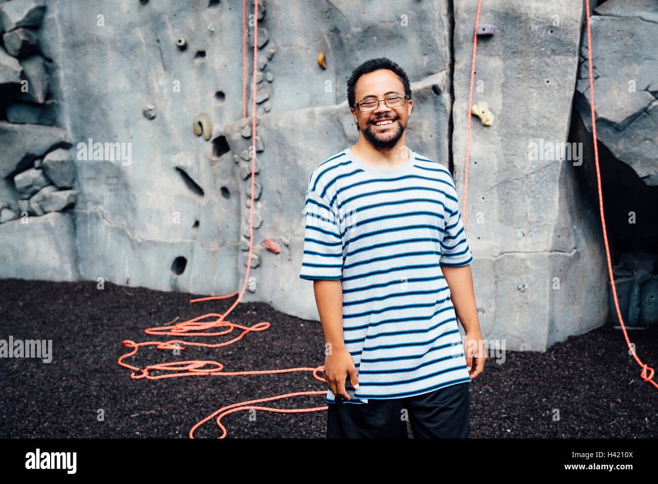 Mixed Race man smiling near rock climbing wall Stock Photo