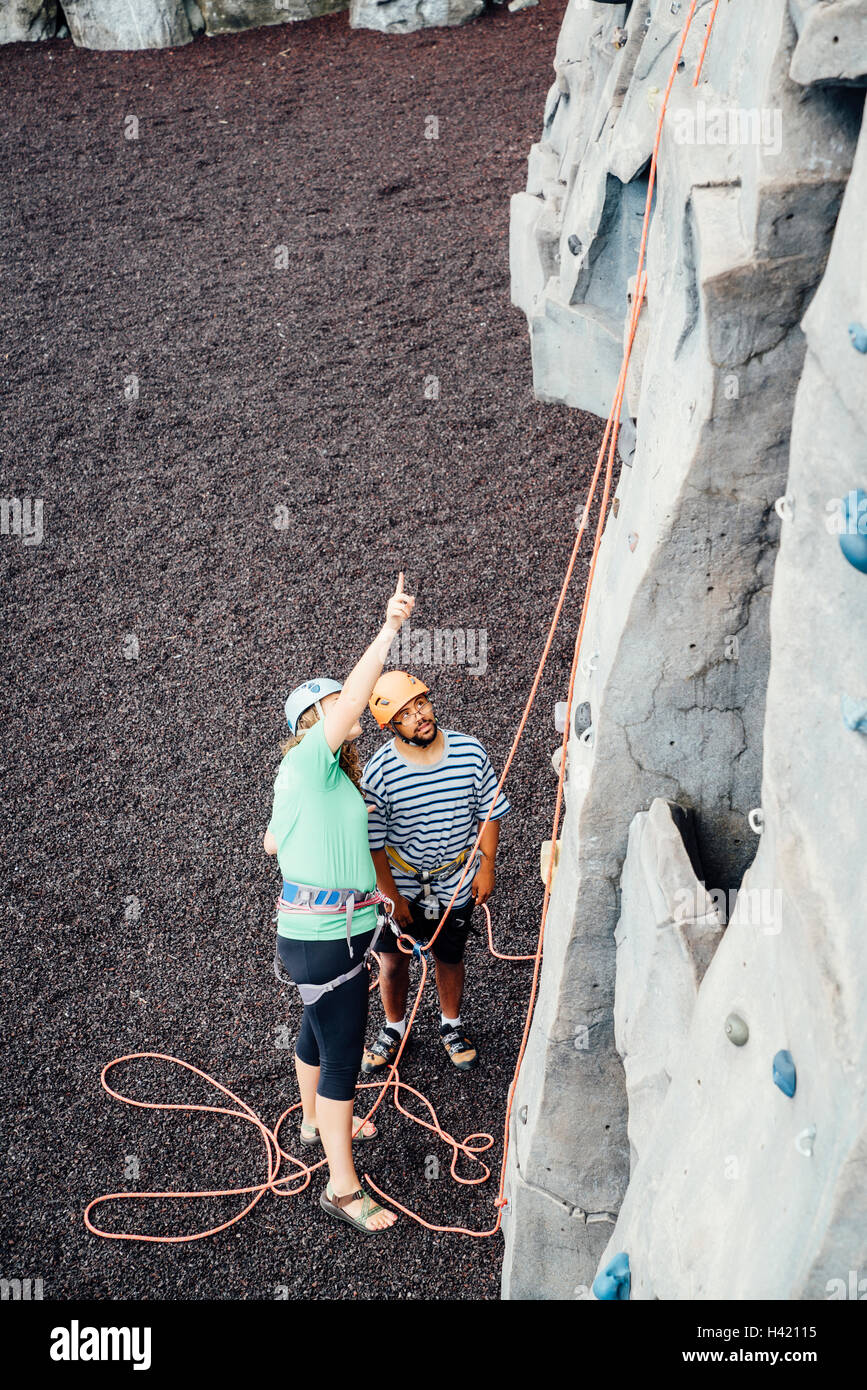 Woman and man looking up at rock climbing wall Stock Photo