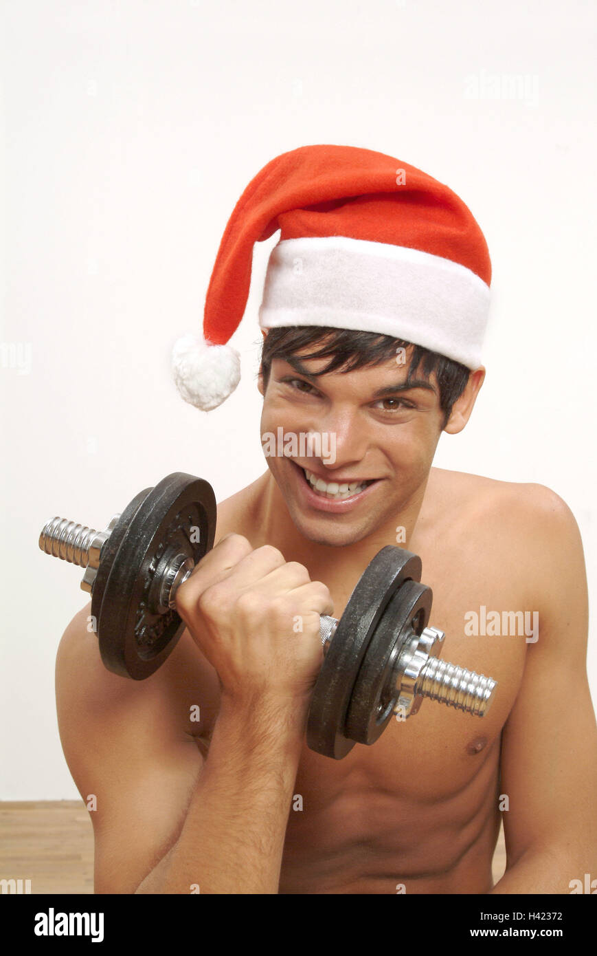 Man, young, smile, free upper part of the body, Santa's hat, dumbbell training, portrait, man's portrait, 20-30 years, dark-haired, well-trained, training, muscle training, weight training, dumbbell, short dumbbell, force, strain, Santa Claus, Santa, Sant Stock Photo