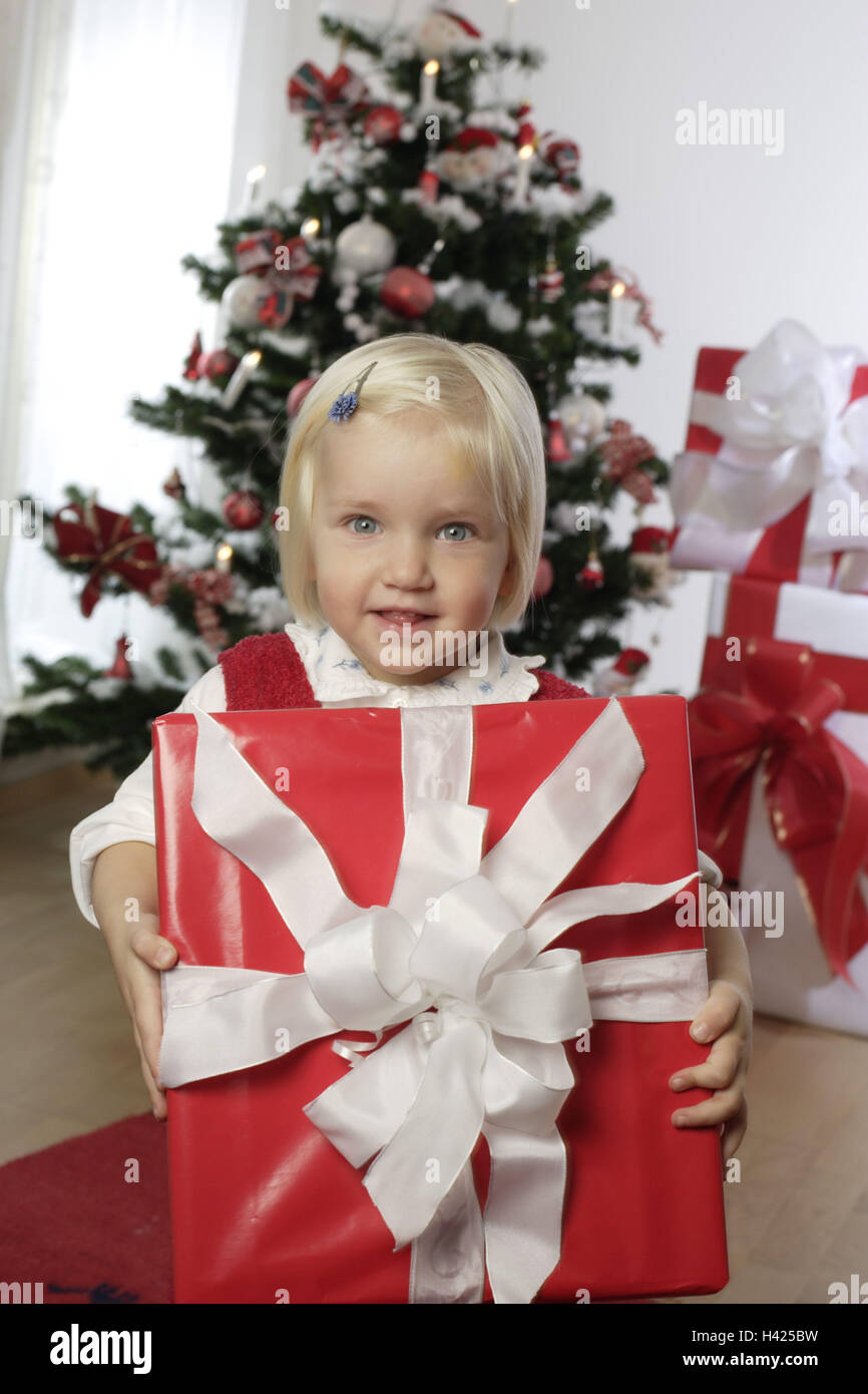 Christmas, Weihnachtsbaum, Bescherung, girls, gift, holding, Halbporträt Living rooms, Christmas tree, child,  3-5 years, childhood, gift, Christmas gift, Christmas gifts, packages, red-white, gives, gives, joy, anticipation, expectation, surprise, Christ Stock Photo