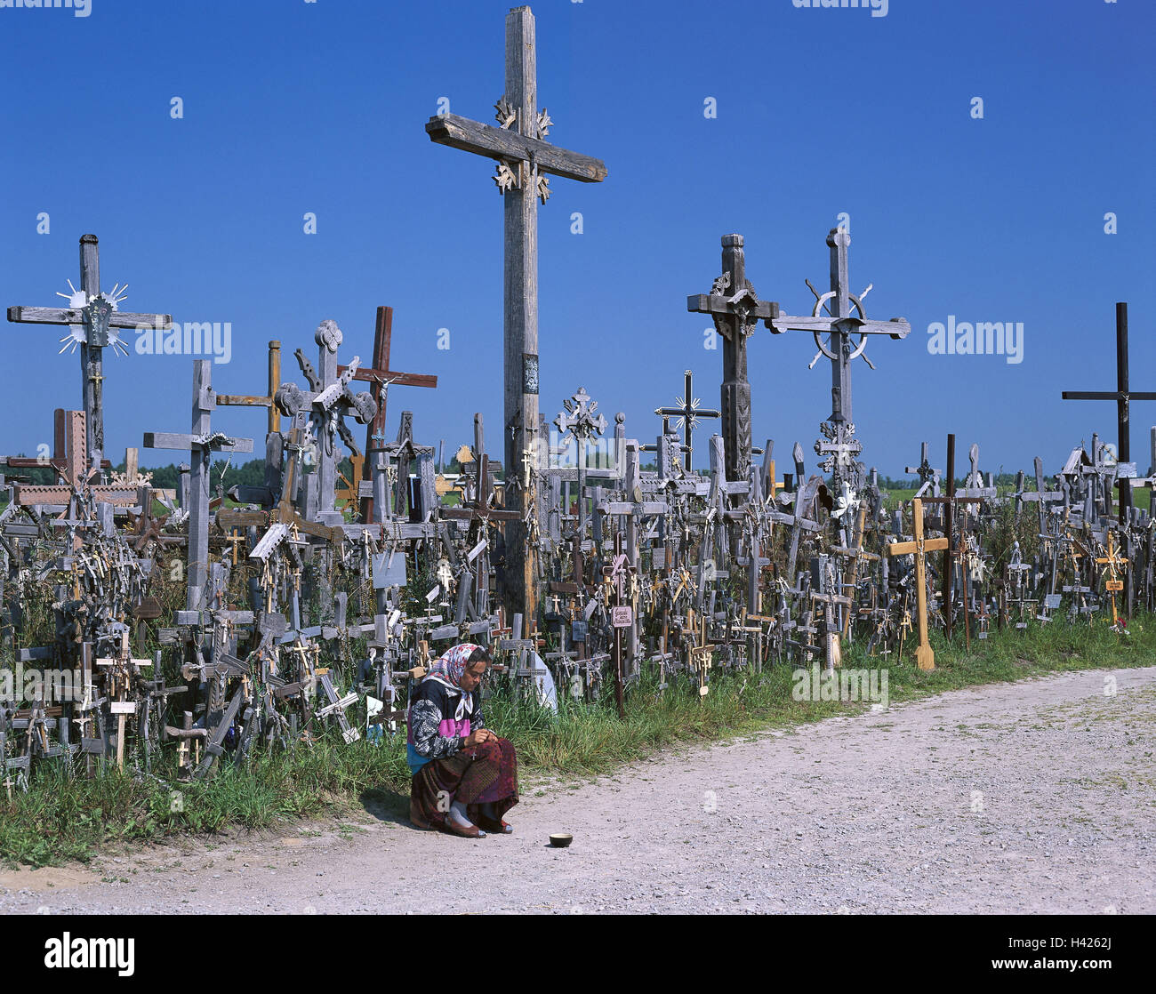 Lithuania, close Siauliai, cross mountain, Kryziu Kalnas, woman, sit, prayer, beg, no model release!, Europe, Nordosteuropa, the Baltic States, Lietuva, Lietuvos Respublika, Schaulen, Schawli, mountain the crosses, hills, shrine, national shrine, place pilgrimage, pilgrim's site, Kriziu Kalnas, pilgrim's crosses, wooden crosses, crucifixes, rosaries, offering, contributions, offerings, carving, national icon, hope, faith, religion, Christianity, place of interest, landmark, headgear, headscarf, humility, devotion, poverty, dished plate Stock Photo