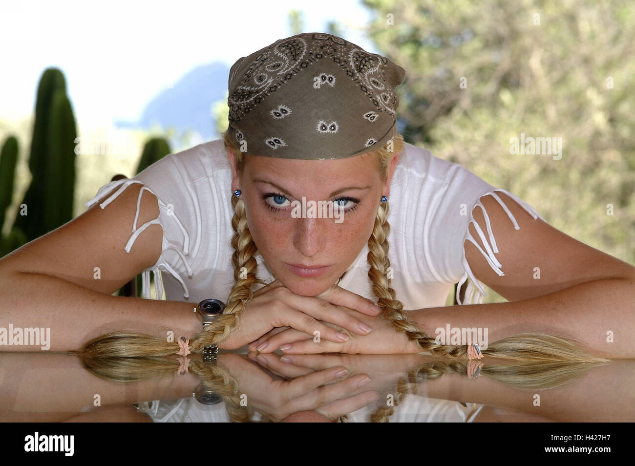 Woman, young, blond, braids, kerchief,  Glass table, resting, serious,  knocked down, gaze camera,  24 years, 20-30 years, emotion, sorrowfully, secluded, depressed, problem, sorrow, worries, longing, lovesickness, alone Stock Photo