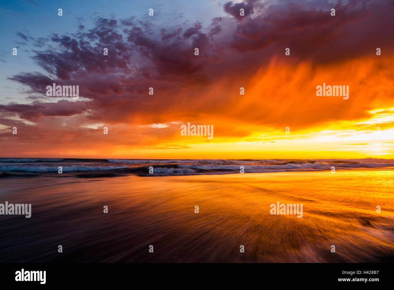 Scenic sunset sky reflecting in shallow ocean water on the beach in Del Mar, California Stock Photo