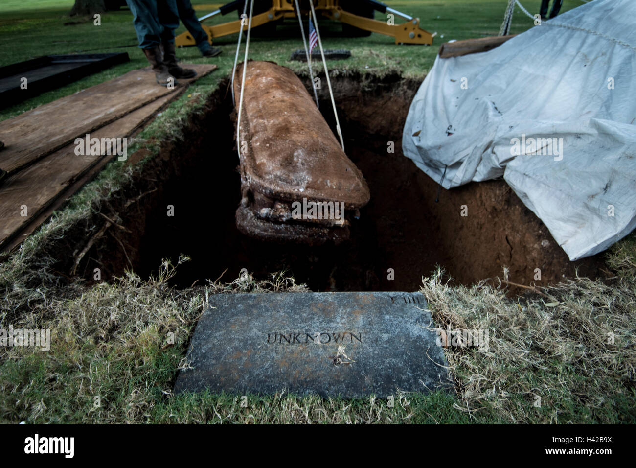 A casket carrying the unidentified remains of a U.S. soldier is lifted from its grave at the National Memorial Cemetery of the Pacific October 3, 2016 in Honolulu, Hawaii. The DPAA are transporting the remains to a lab for DNA analysis with the hope of identifying the remains. Stock Photo