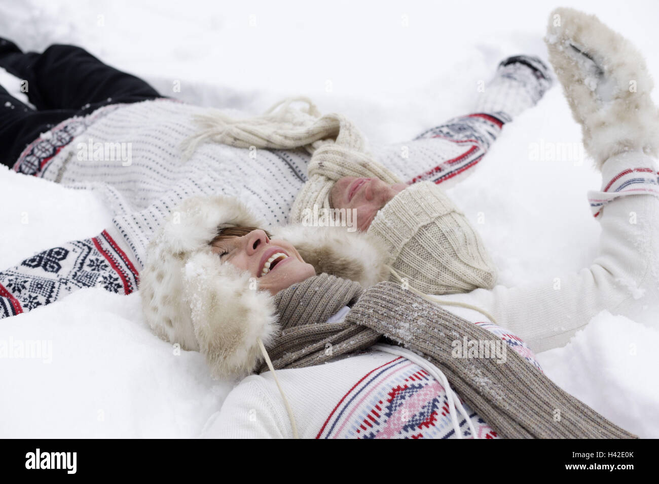 Pair, young, snow, lies, laughs   Series, 20-30 years, head at head, partnership, relationship, love, happily, leisure time, outside, in the winter passport snow fun winters, clothing, wintry, winter clothing, caps, scarfs, gloves, relaxation, recuperation, fun, enjoys Stock Photo