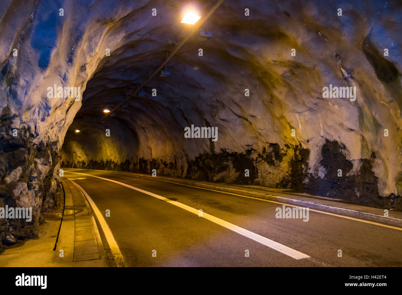 Two lane road tunnel in Switzerland with sprayed concrete walls. Stock Photo