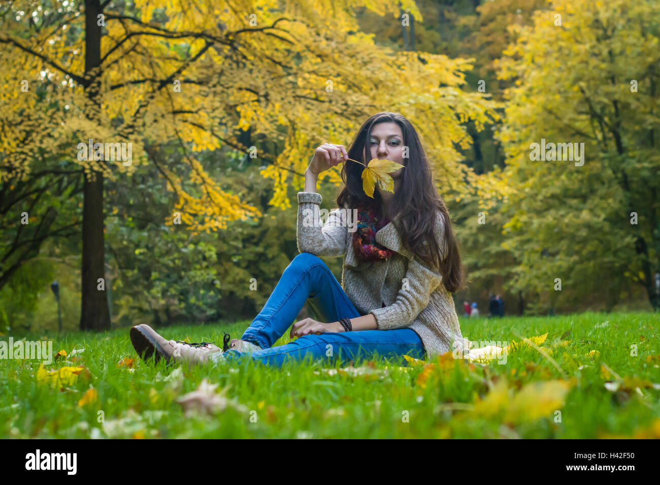smiling, happy girl sitting on green grass in autumn park Stock Photo ...