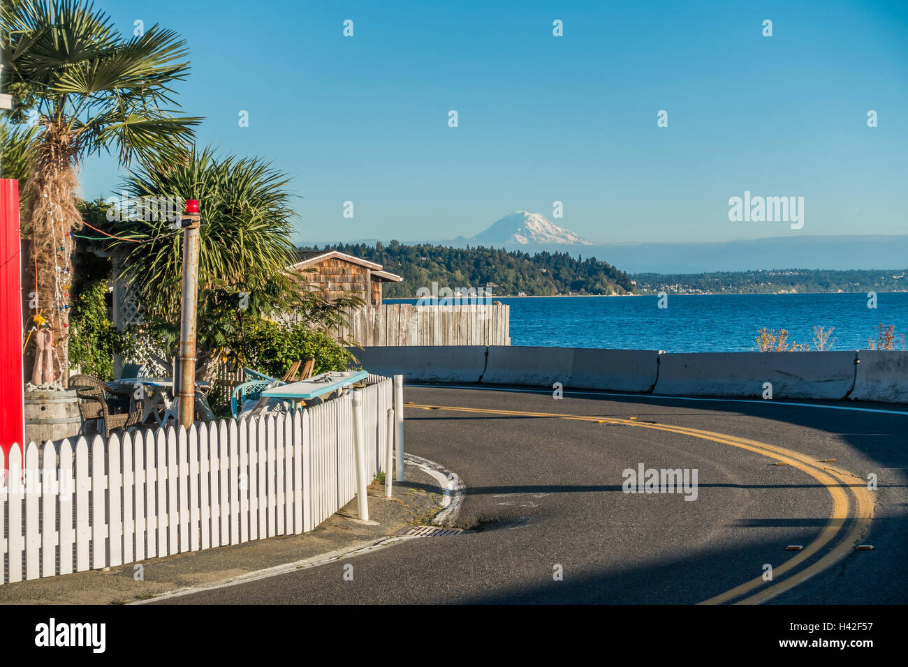 A road curves with Mount Rainier across the water at There Tree Point in Burien, Washington Stock Photo