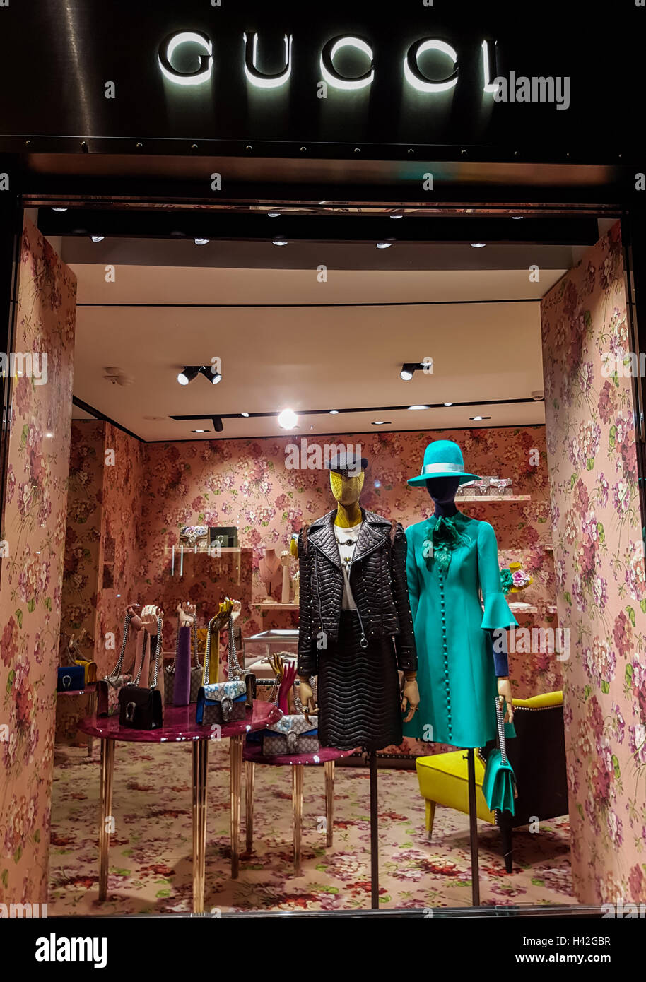 Gucci luxury bags, clothes and shoes sit displayed for sale inside a Gucci store. Stock Photo