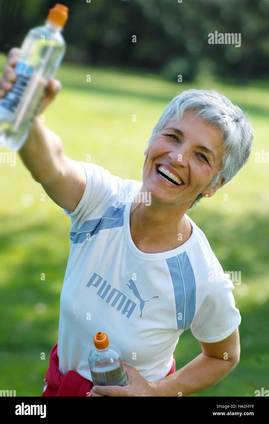 Senior, sportily, water flasks, hold, point, laugh, half portrait, 50-60 years, woman, sportswoman, rest, disengage, rest, water flask, mineral water, water, thirst, Durstlöscher, drink, alcohol-free, balance, happily, cheerfulness, tuning positively, amusements, fitness, activity, sport, leisure time, hobby, summer, outside Stock Photo