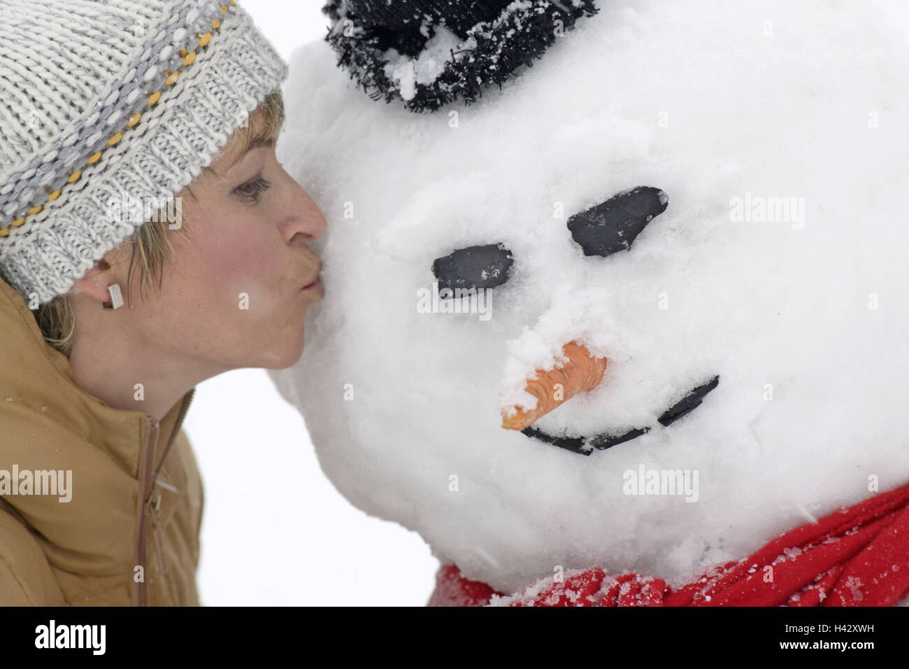 Woman, winter jacket, cap, snowman,,  Kiss, side portrait, winters,   Series, 20-30 years, winter clothing, rope cap, headgear, snow figure, kiss, fun, pleasantry, jokes, freely, cheerfully, naturalness, joy, leisure time, zest for life, Lifestyle, outside, winter vacation, vacation,, Stock Photo