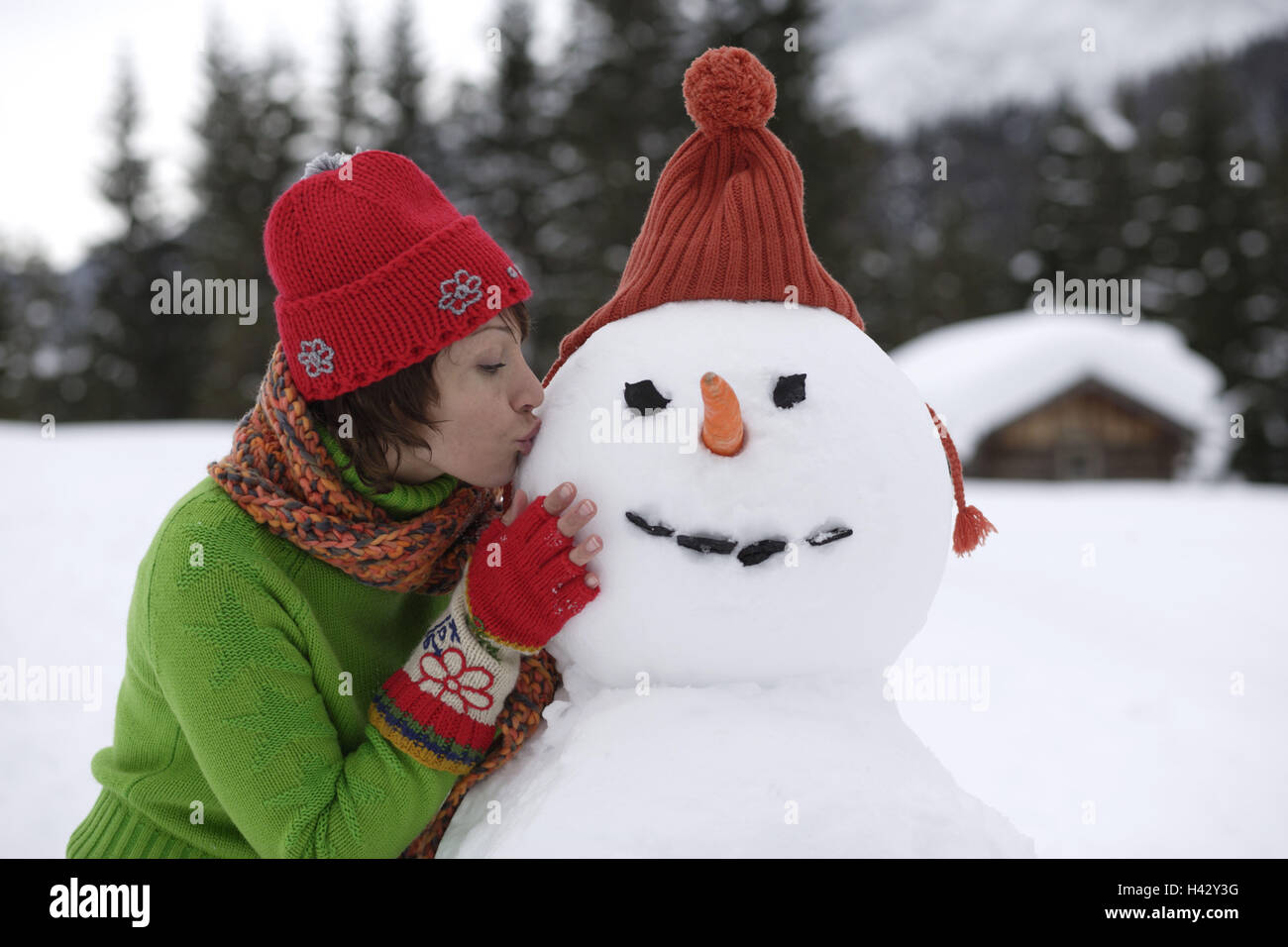 Woman, smiles, snowman, embrace,  kisses, portrait  Series, women portrait, 20-30 years, young, nicely, sympathetically, snow, vacation, leisure time, fun, zest for life, happiness, clothing, winter clothing, cap, scarf, snow fun, in the winter passport, outside, winters, happily, affection, kiss Stock Photo
