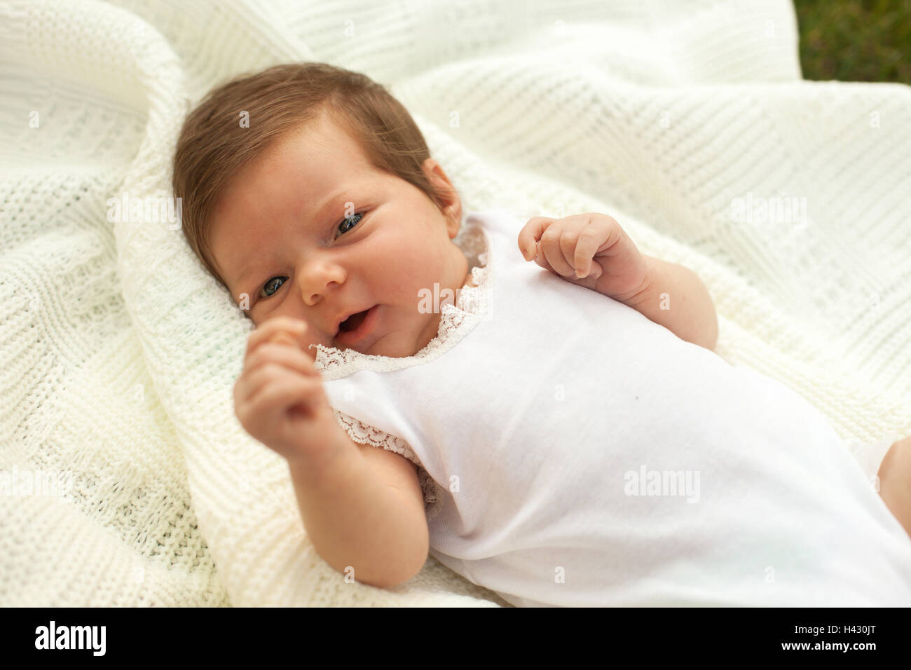 Baby lying on the blanket on the grass Stock Photo