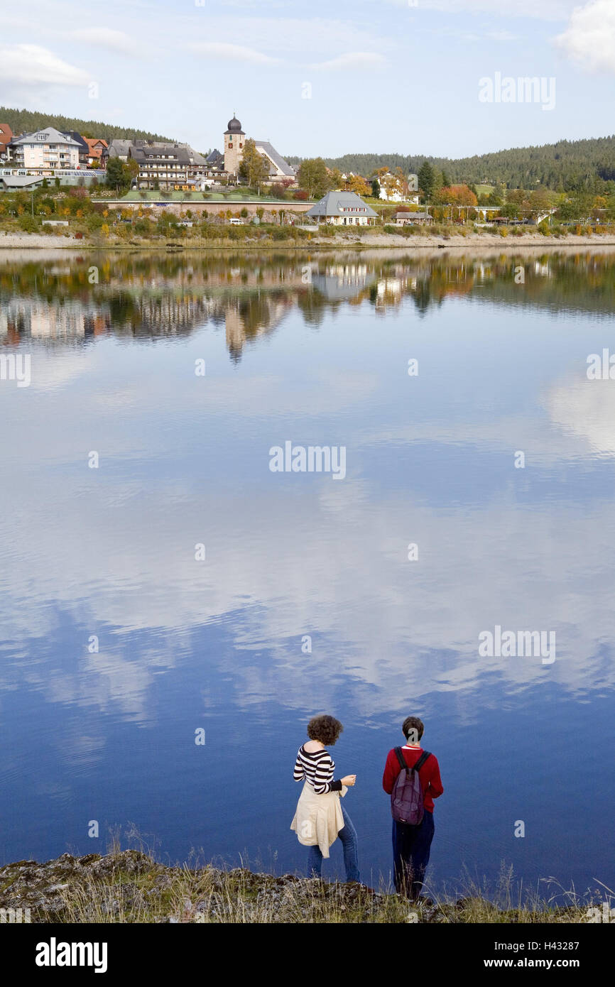 Germany, Baden-Wurttemberg, Black Forest, Schluchsee, local view, lakeside, couple, back view, lake, shore, mirroring, water surface, heaven, tourism, person, tourist, houses, church, steeple, Stock Photo