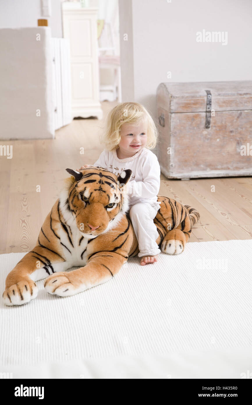Living rooms, toddler, girls, cheerfully, play, sits, material-animal, tigers, apartment, people, child, 1-2 years, small, blond, smiles, however happily cheerfully, freely, with pride, rides, material-tigers, Schmusetier, Kuscheltier, big, childhood, at Stock Photo