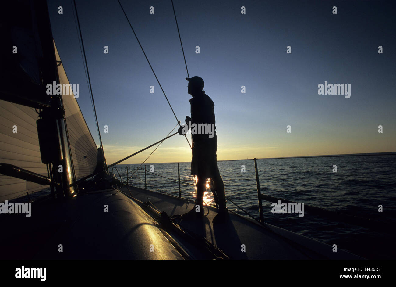 Sail yacht, man, deck, silhouette, evening mood, coxswain, sail, trim, wind, sailing ship, yacht, sailboats, boat, sailings, water sport, sport, sailing trip, regatta, hobby, navigation, maritime, sea, water, waves, horizon, distance, wind, width, vacation, loneliness, freedom, the Baltic Sea, only, mood, evening, cloudless, sundown, romantically, yachtsman, trimmer, Stock Photo