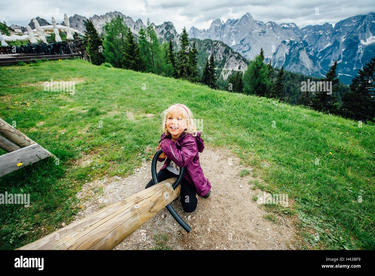 Caucasian girl on seesaw near mountain range, Tarvisio, Vienna, Austria Stock Photo