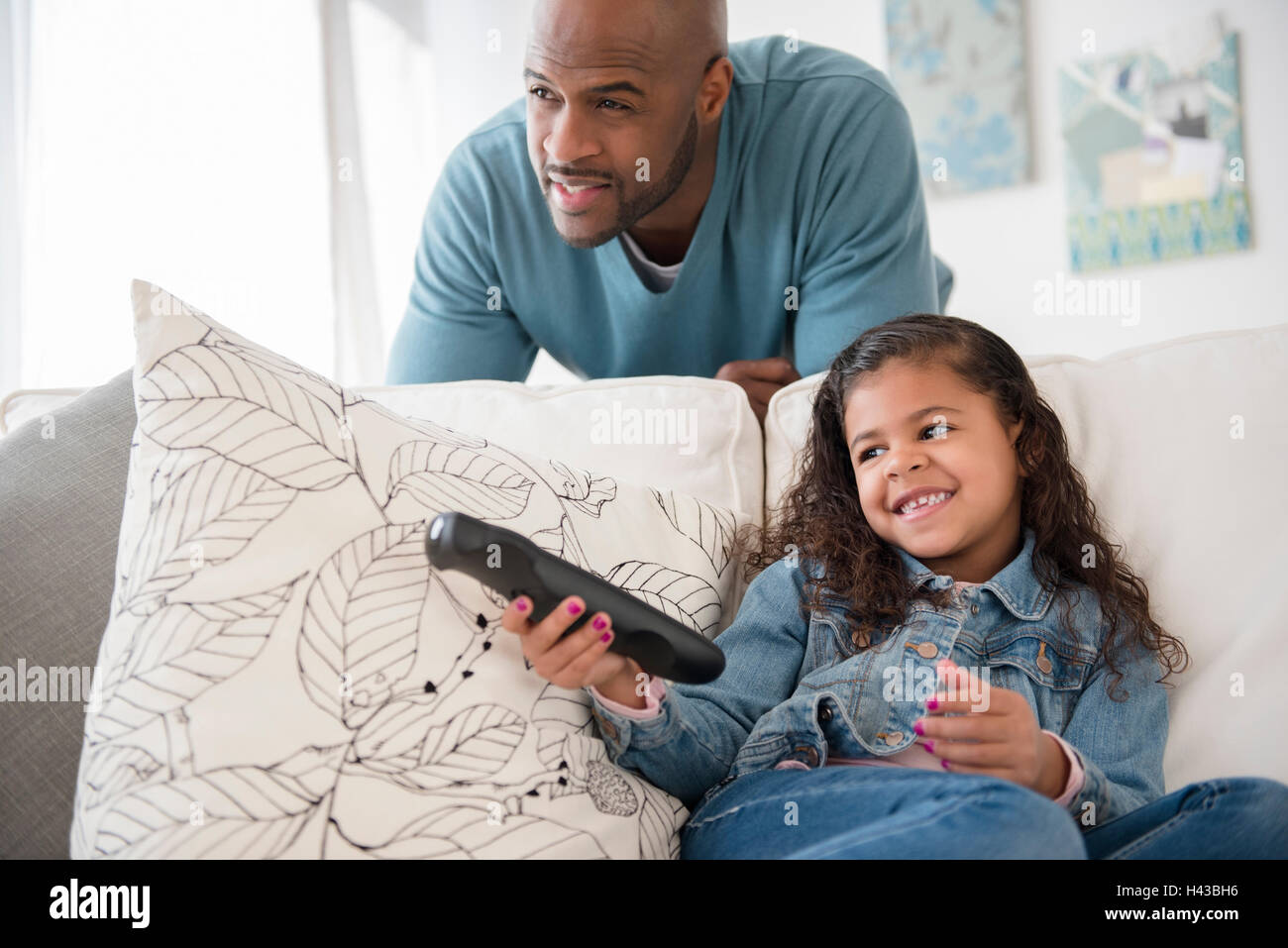 Father and daughter watching television on sofa, Stock Photo