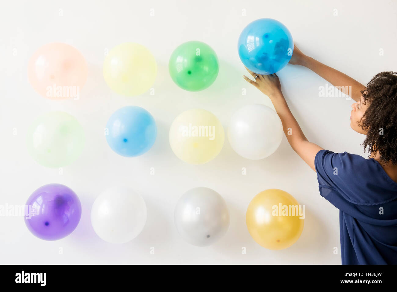 Black woman attaching balloons to wall Stock Photo Alamy