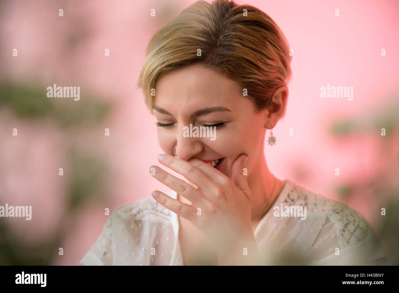 Caucasian woman covering mouth while laughing Stock Photo