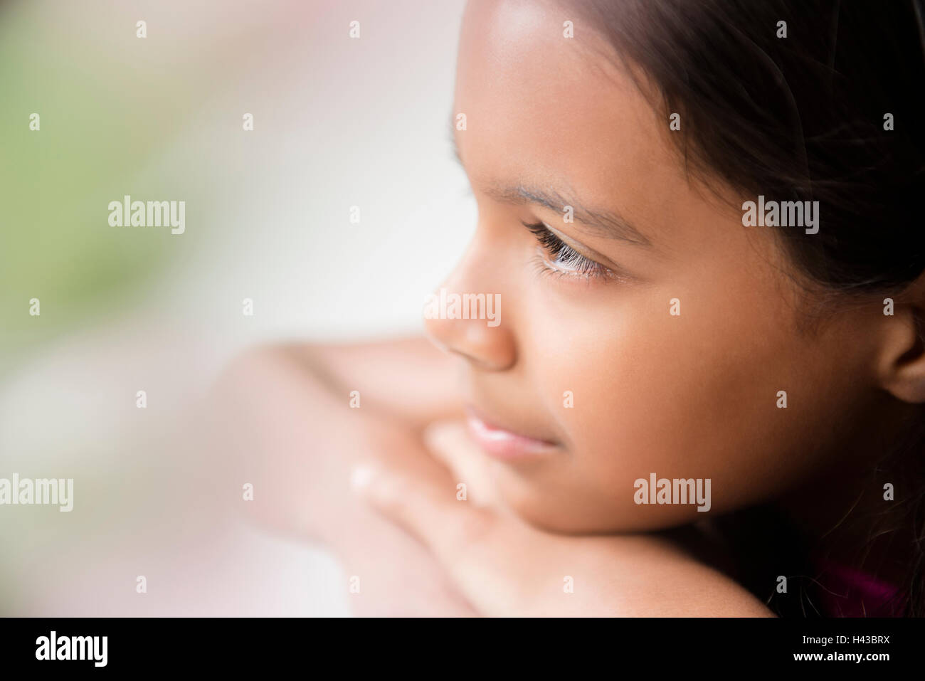 Pensive Mixed Race girl resting chin on hand Stock Photo
