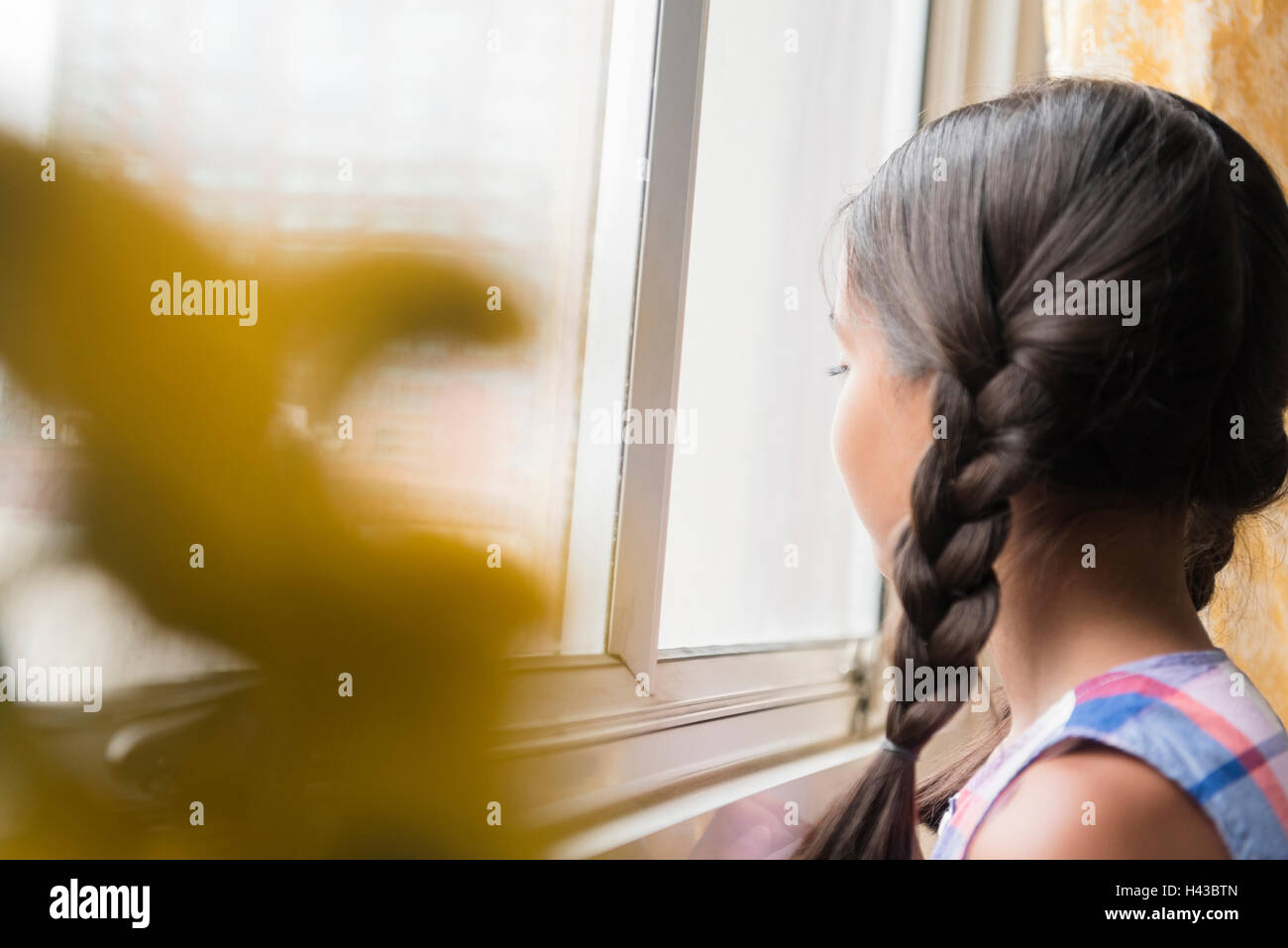 Mixed Race girl looking out window Stock Photo