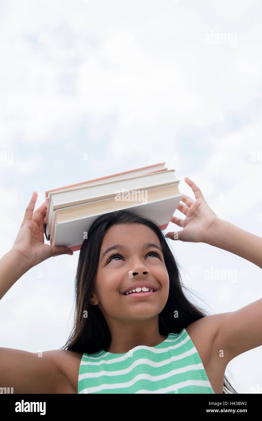 Mixed Race girl balancing books on head Stock Photo