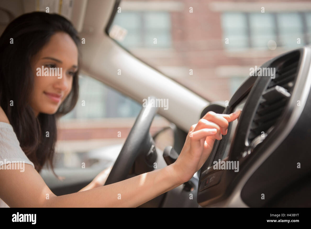Mixed Race woman pressing touch screen in car Stock Photo