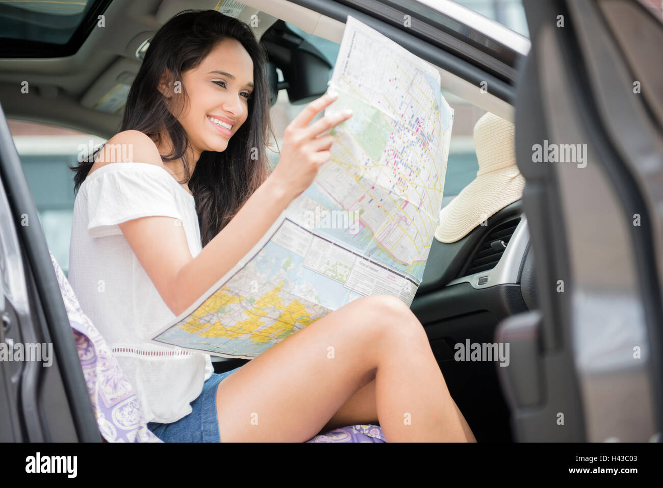 Mixed Race woman sitting in car reading map Stock Photo