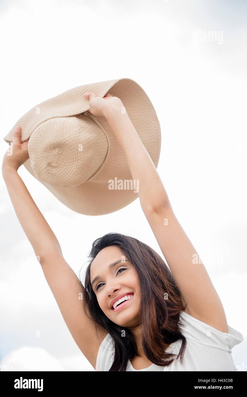 Smiling Mixed Race woman holding sun hat Stock Photo