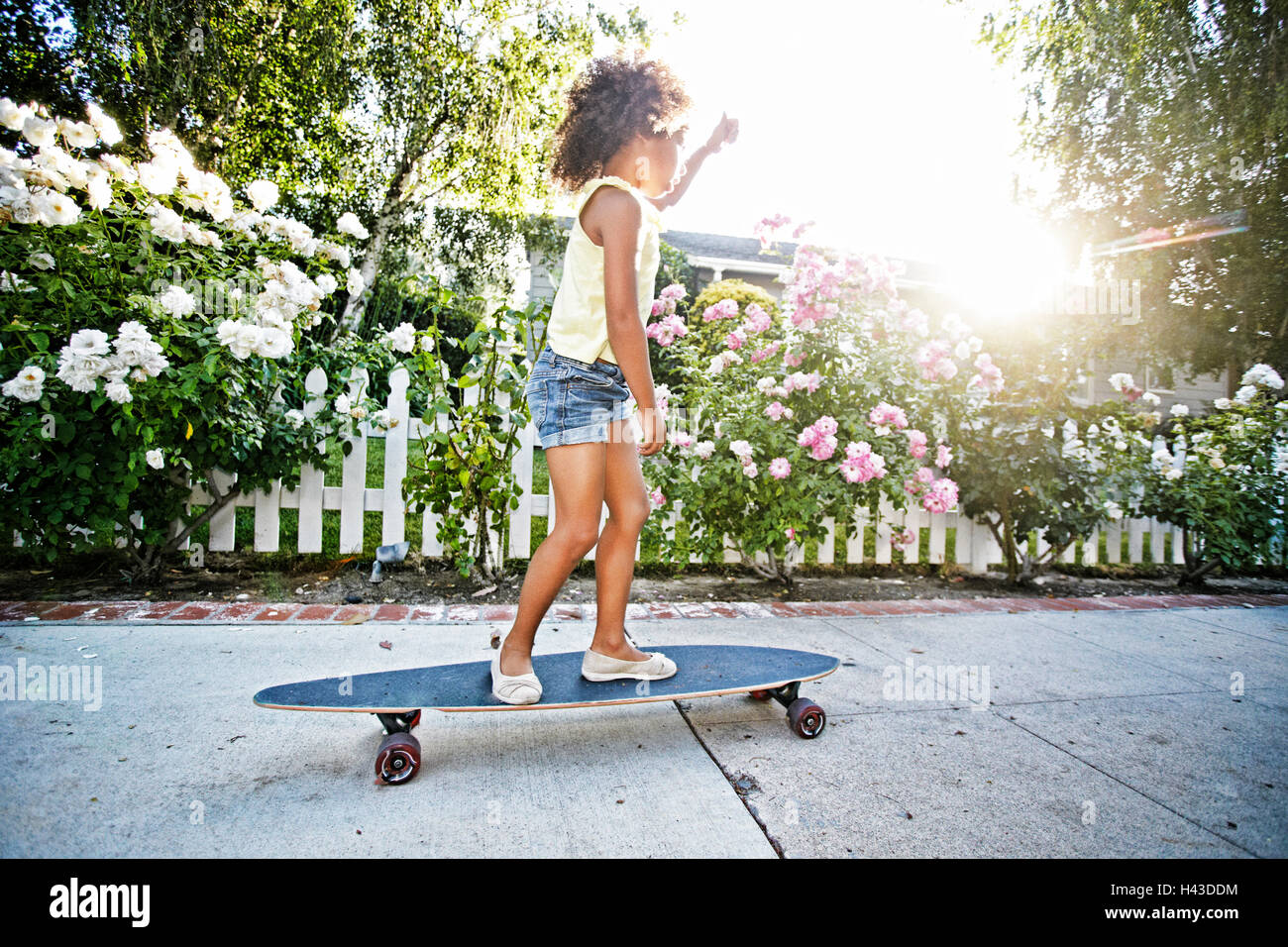 Mixed Race girl skateboarding on sidewalk Stock Photo - Alamy